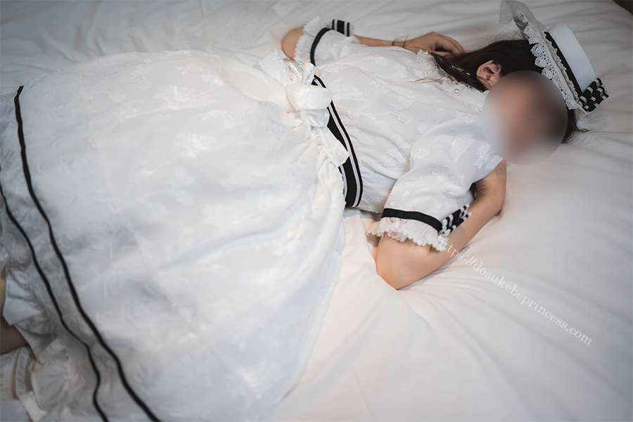 白いロリータワンピースを着てベッドにうつ伏せになる女の子