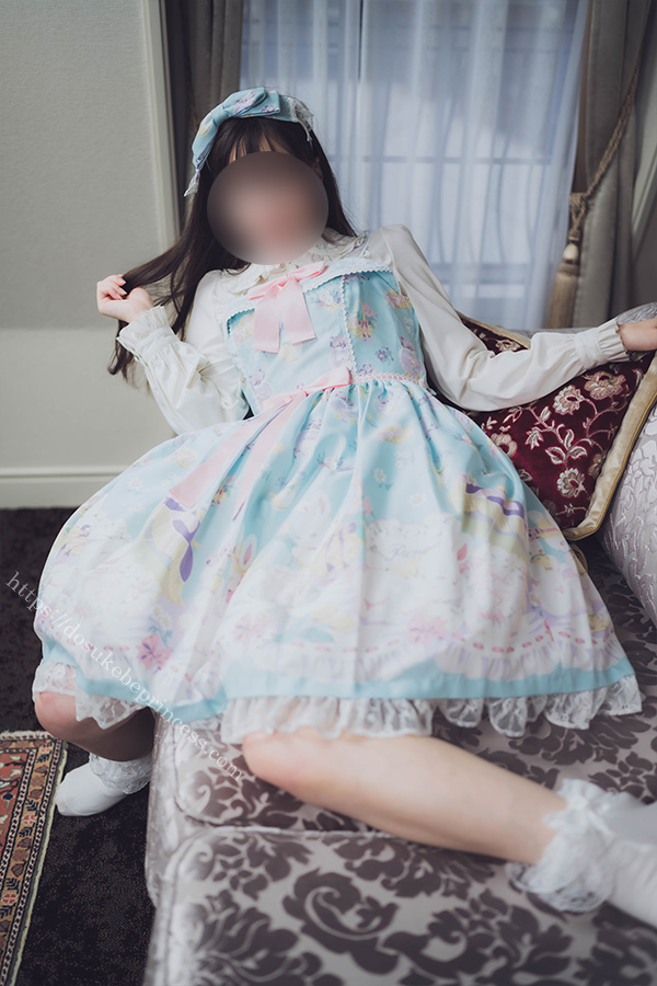 ホテルのソファの上に寝そべってポーズをとるロリィタ服の女の子